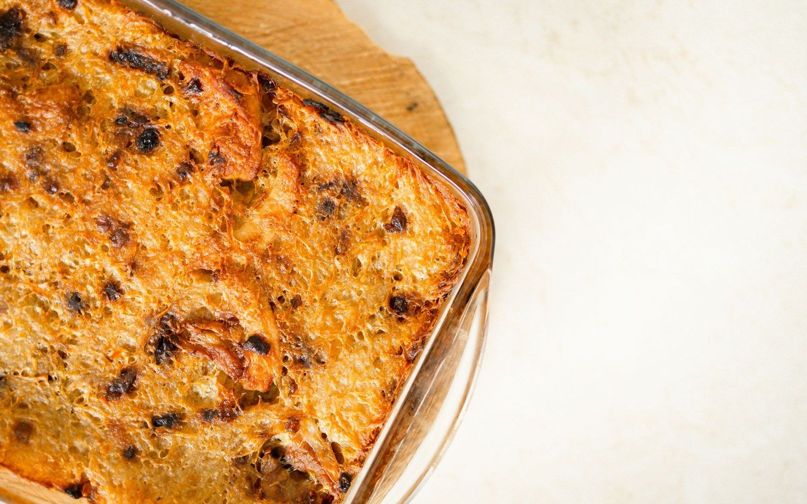 Golden-brown bread and butter pudding with a crisp caramelized top in a glass dish