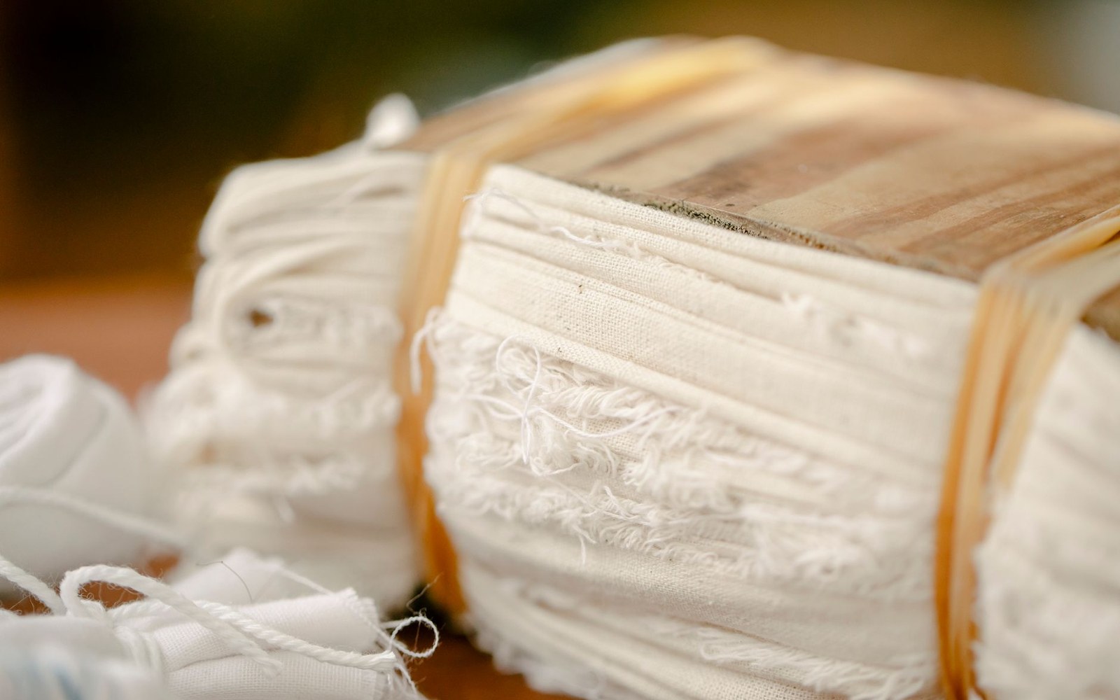Bundles of folded white fabric bound with rubber bands on a wooden surface