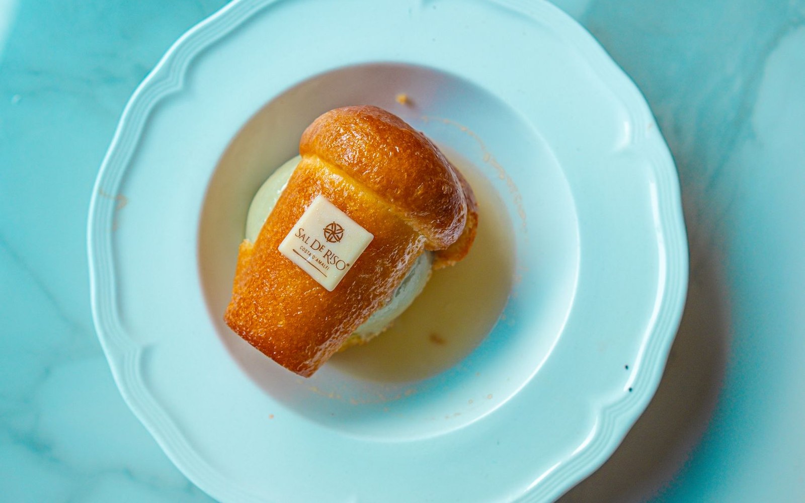 Golden brioche bun filled with ice cream, branded with a small paper label, on a plate